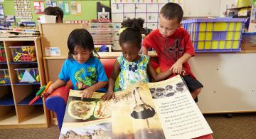 Image of 3 children reading a giant book