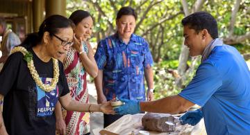 Student handing donor a bowl of poi