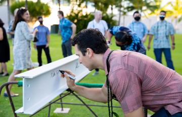 A man signs the beam marking the topping off of Koula.
